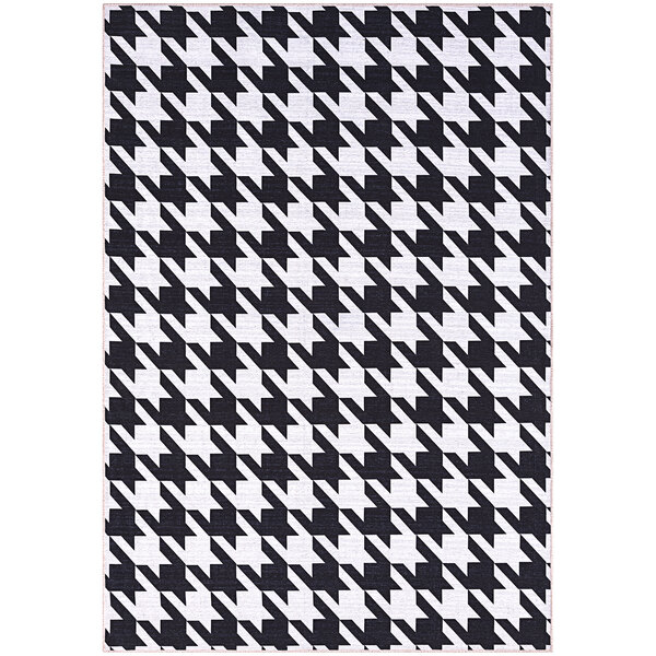 A cream area rug with a black and white geometric houndstooth pattern and white border.