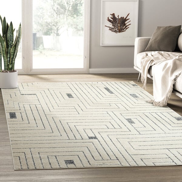 An Abani Cabo Collection cream and gray geometric labyrinth area rug on a wood floor.