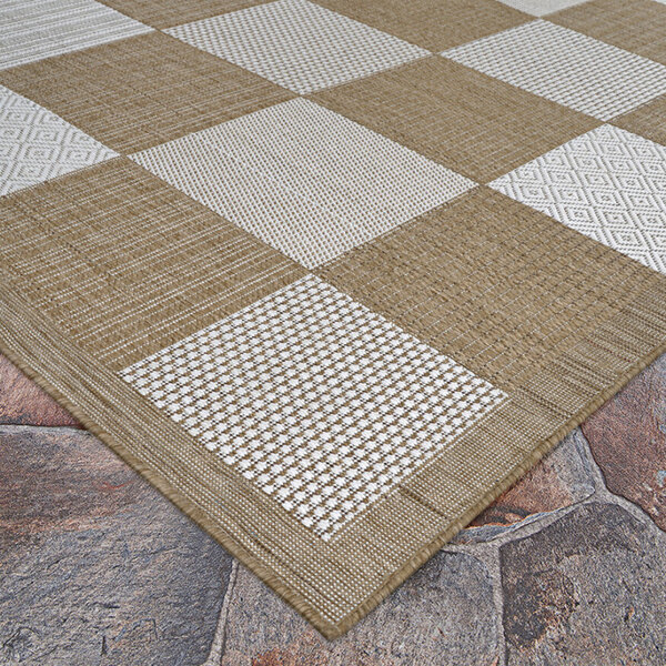 A Couristan light brown and ivory checkered area rug on a stone floor.