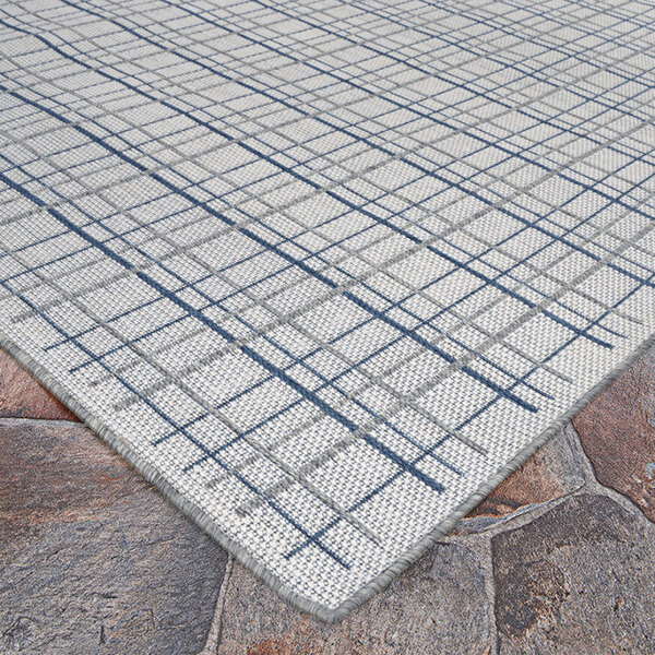 An ivory rug with a blue check pattern on a stone surface.