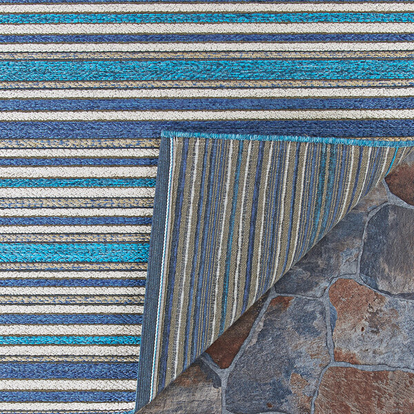 A Couristan Cape Brockton cobalt and teal striped area rug on the ground.
