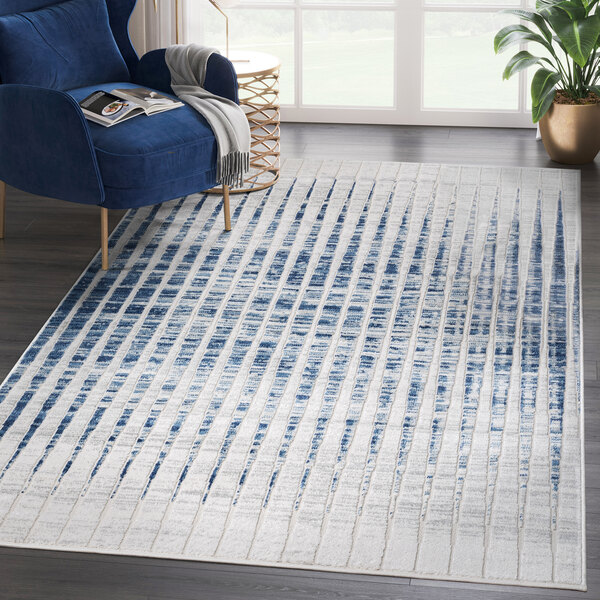 An Abani Atlas Collection blue and gray contemporary vertical lines area rug in a white room with a blue chair.