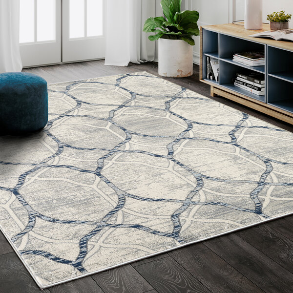 A cream and gray Abani Arto Collection geometric trellis area rug in a room with a white pot plant.