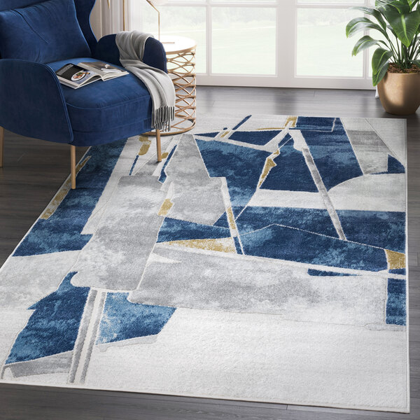 An Abani Atlas Collection blue and gray contemporary abstract block area rug with geometric shapes under a blue chair.