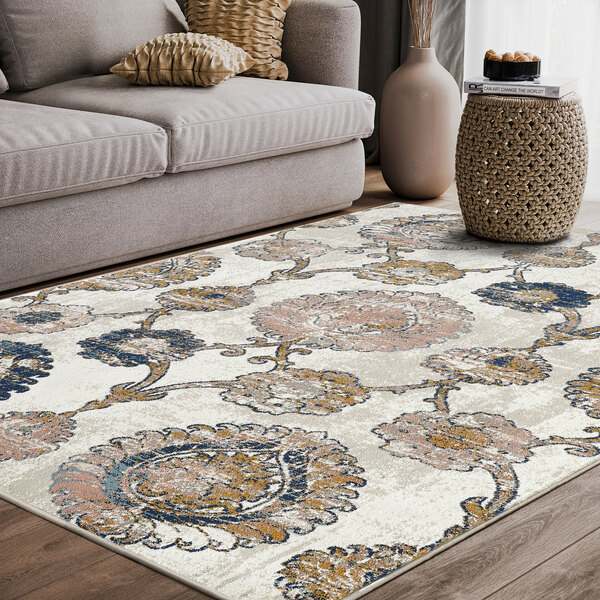 An Abani Arto Collection coral and navy area rug with a distressed medallion design next to a couch.