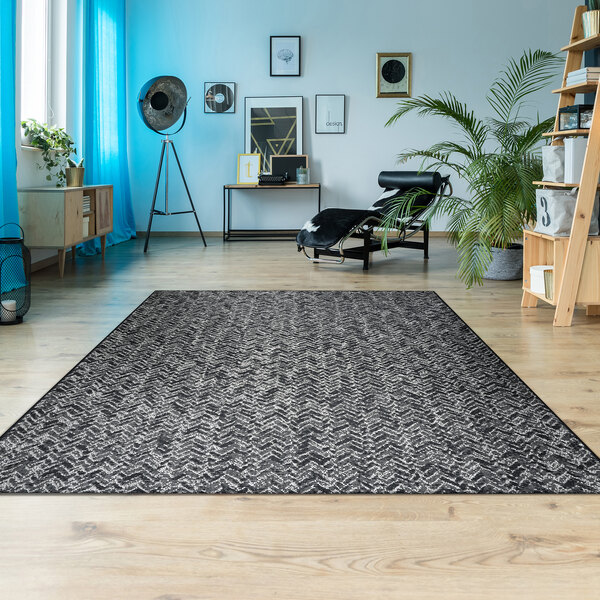 A Couristan Afuera Herringbone area rug in a room with a wooden floor and a chair.