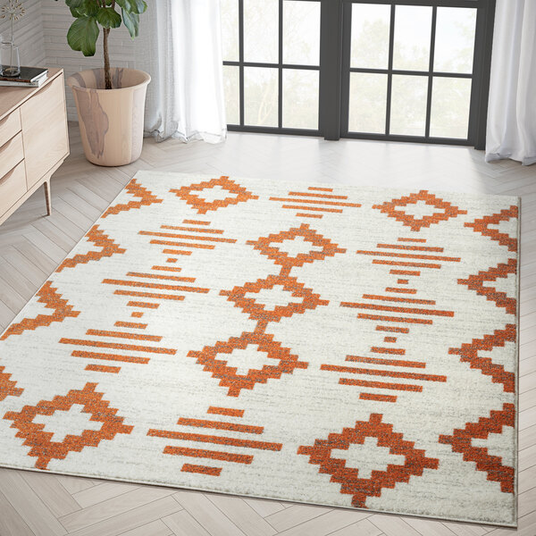 An orange and white Abani Casa Collection area rug with geometric designs on the floor.