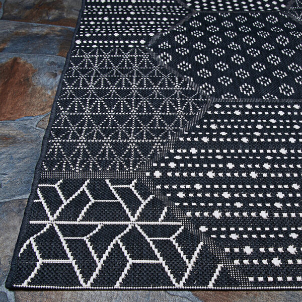 A white area rug with black geometric patterns.
