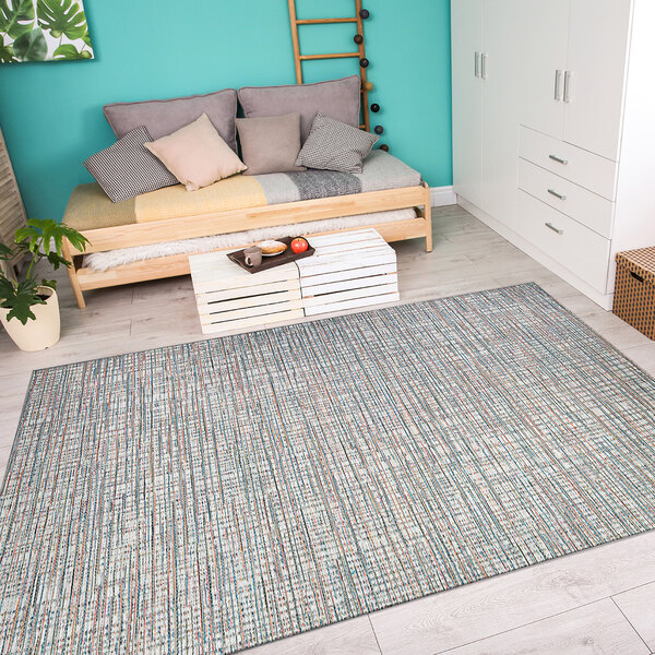An ivory and coral Couristan area rug in a room with a couch and a plant in a pot.