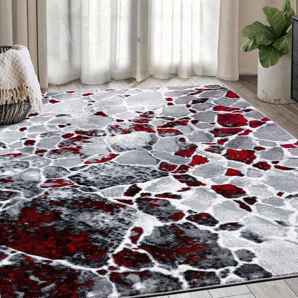 A gray, red, and black area rug with a white pattern in a room.