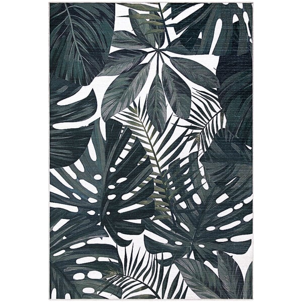 A cream area rug with green tropical leaves on it.