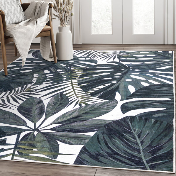 An Abani Parker Collection area rug with a cream background and green tropical leaves on it.