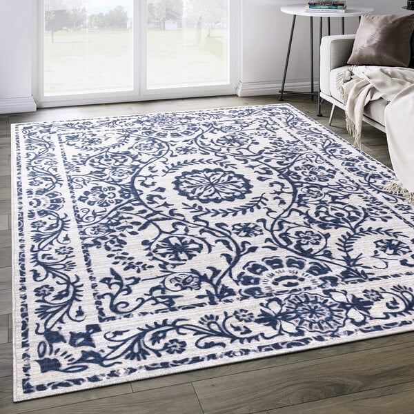 An Abani Parker Collection cream area rug with a blue and white traditional floral medallion design on the floor.