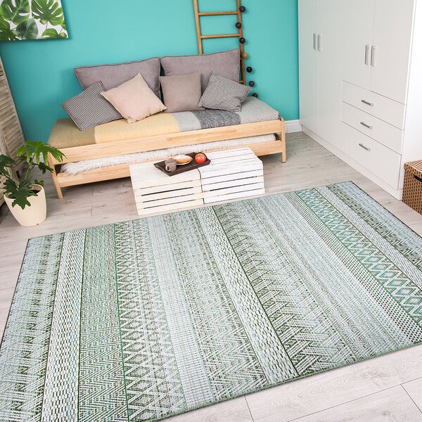 A Couristan palm area rug in a white room with a plant.