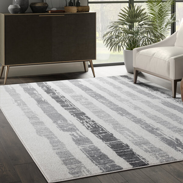 An Abani Casa Collection faded striped Moroccan area rug with gray and white stripes in a white room with a white couch and chair.