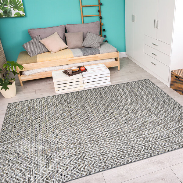 A room with a light brown and ivory Couristan area rug under a couch and table with food.