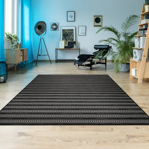 A black and white Couristan Afuera Beachcomber area rug under a chair in a room with wood floors.