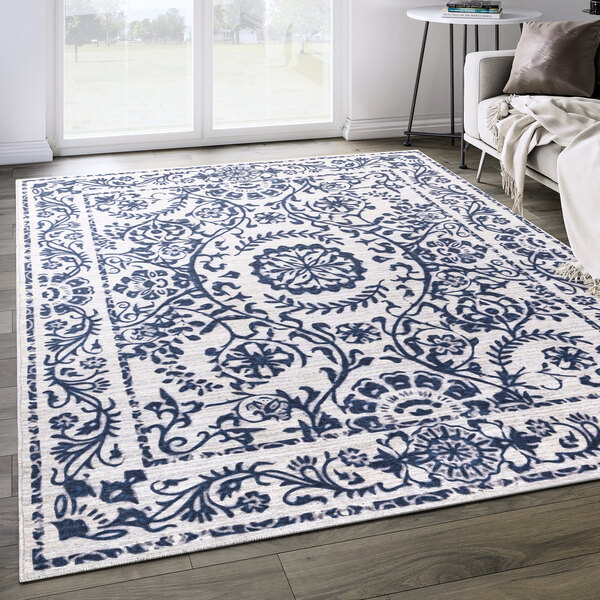An Abani Parker Collection cream area rug with a blue floral medallion design on a floor.