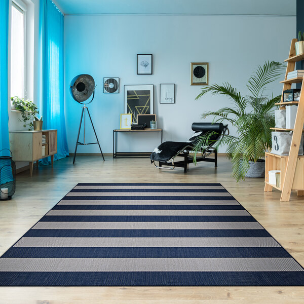 A living room with a blue and white striped Couristan Afuera Yacht Club area rug.