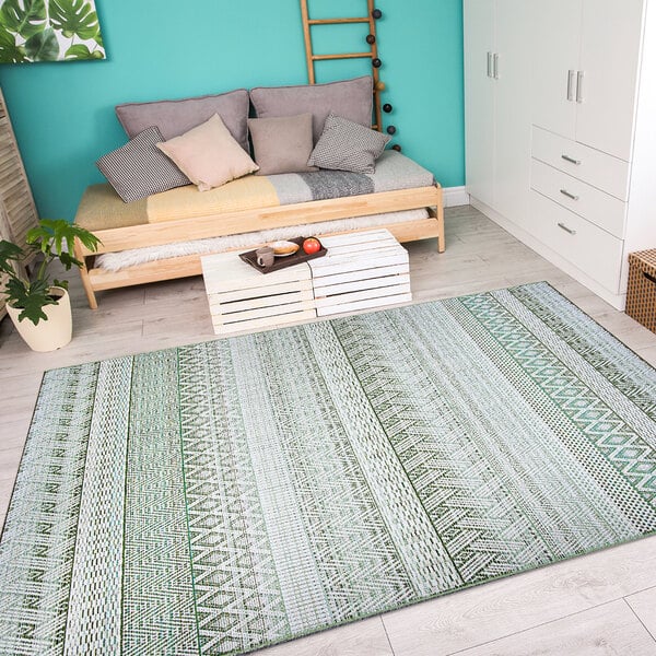 A Couristan Cape Gables palm area rug in a white room with a green plant in a pot.