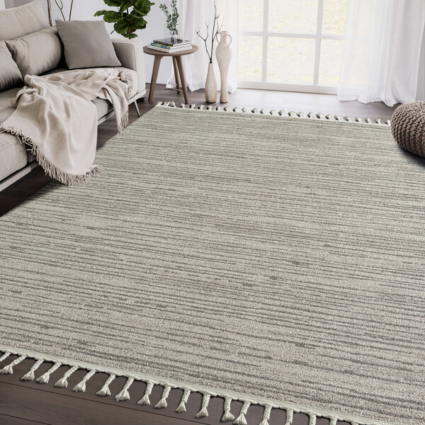 An Abani Layla Collection beige and brown area rug with fringes on a wood floor.