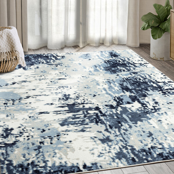 A blue and white Abani Arto Collection area rug with abstract designs on the floor.