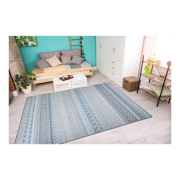 A blue and white Couristan Cape Gables area rug in a room with a wood floor and a couch.