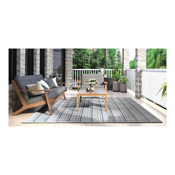 A table and chairs on an ivory and blue Couristan area rug on a patio with a vase of white flowers.