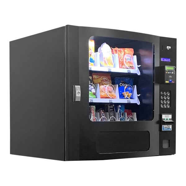 A Seaga black countertop vending machine with snacks behind a glass door.