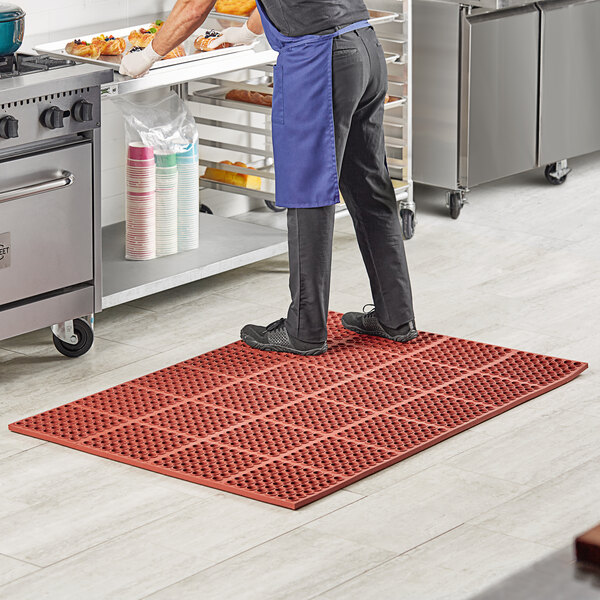 A man standing on a red Lavex anti-fatigue floor mat in a kitchen.
