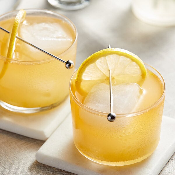 Two glasses of lemonade with ice and lemon slices on a table.