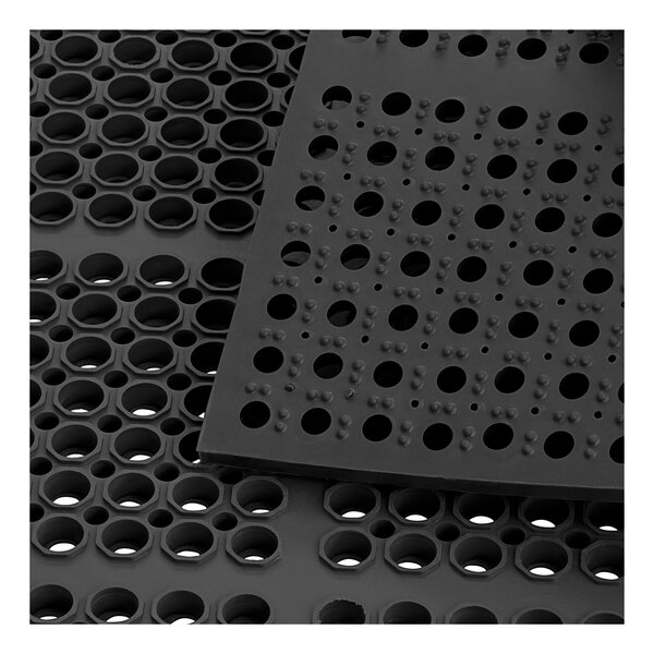 A close-up of a Lavex black rubber anti-fatigue floor mat with holes in it.