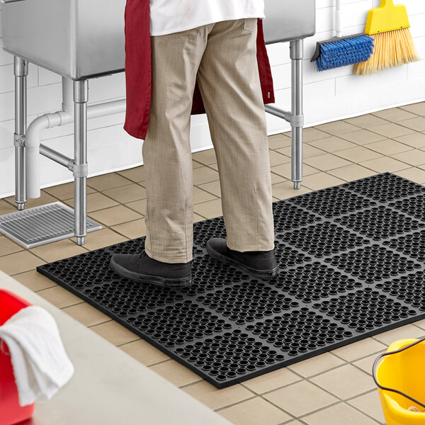 A man standing on a Lavex black anti-fatigue floor mat.
