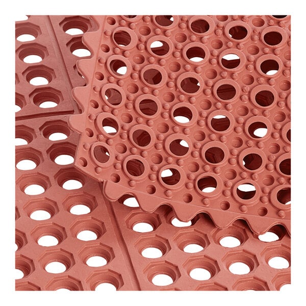 A pile of red rubber Lavex anti-fatigue mats with holes.