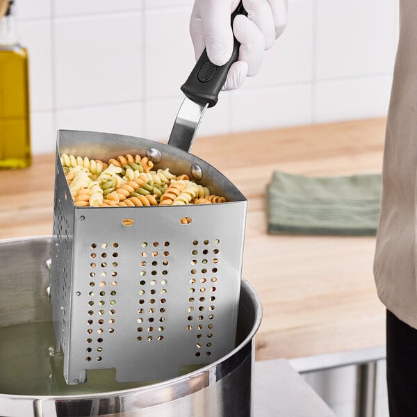 A person holding a Vollrath Wear-Ever stainless steel wedge colander with pasta in it over a pot.