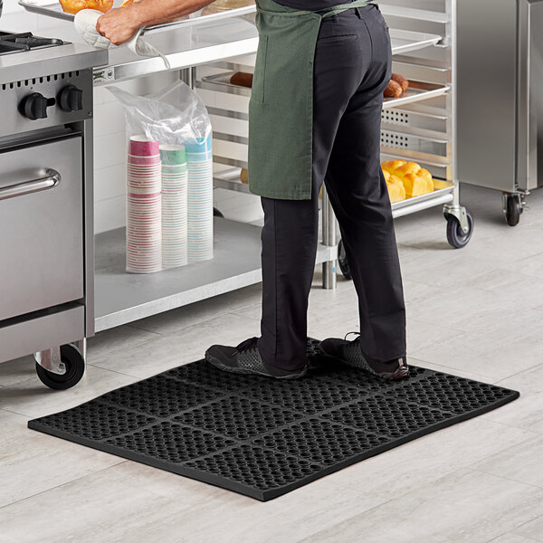 A man standing on a Lavex black anti-fatigue floor mat in a kitchen.
