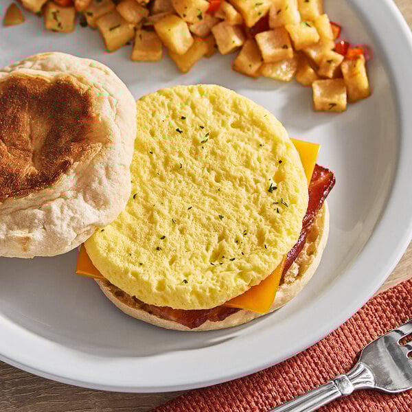 A white plate with a breakfast sandwich made with a Papetti's scrambled egg patty and a side of potatoes.