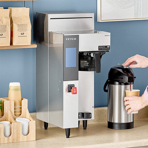 A person pouring coffee into a black and silver coffee machine.