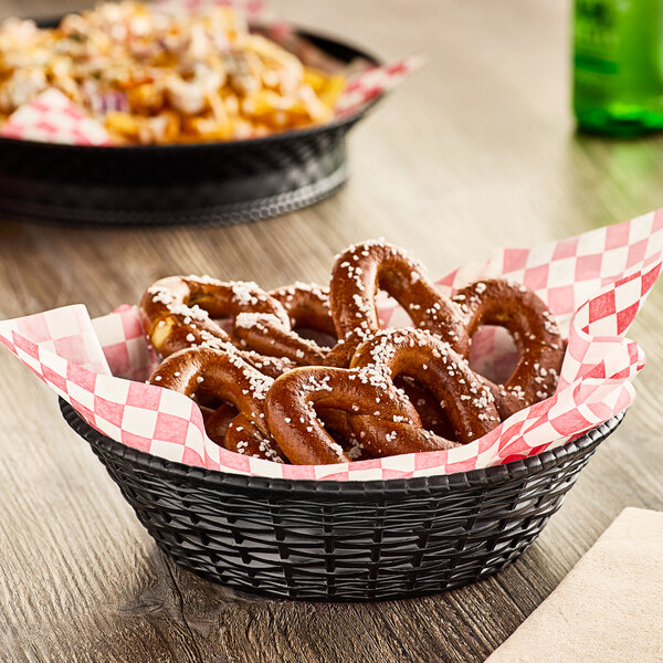 A Carlisle black plastic serving basket filled with pretzels on a table.