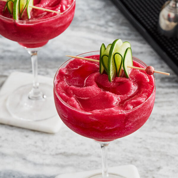 Two glasses of pink prickly pear drinks on a table.