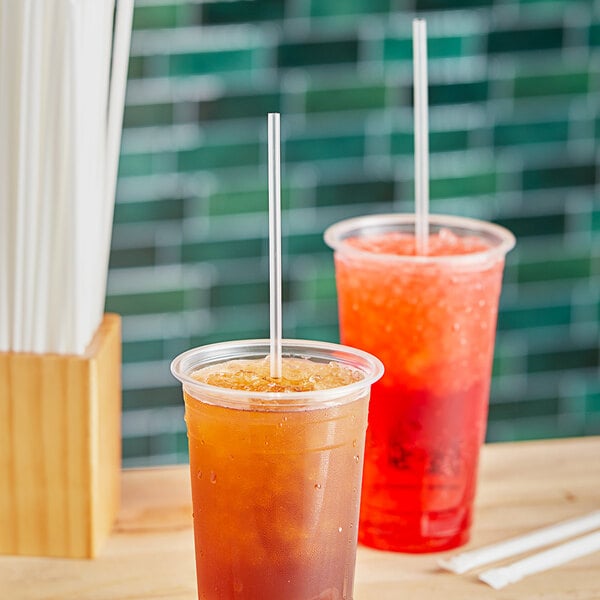 A plastic cup with a Choice jumbo clear wrapped straw in a brown drink.