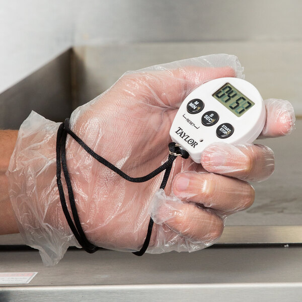 A person holding a Taylor digital kitchen timer/stopwatch with lanyard.