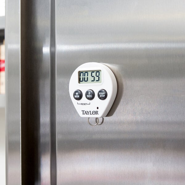A white Taylor digital kitchen timer on a silver metal surface.