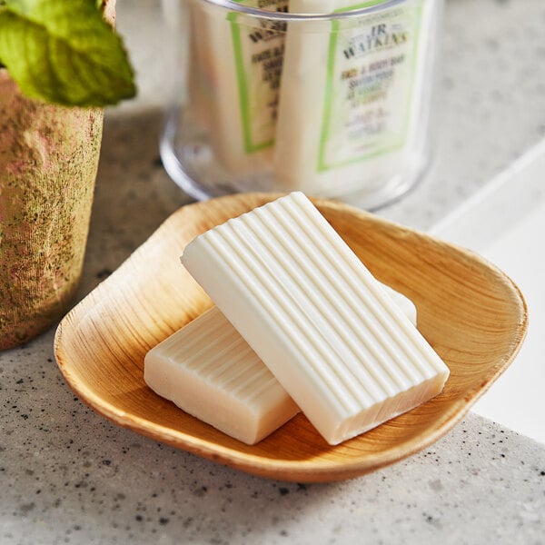 A wooden dish with white JR Watkins Aloe and Green Tea Face and Body Bar Soap bars.