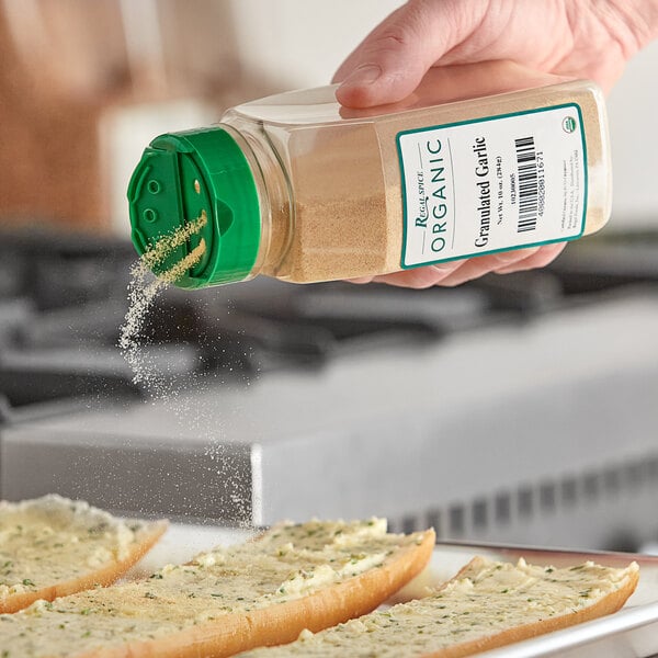 A person sprinkling Regal Organic Granulated Garlic on bread.