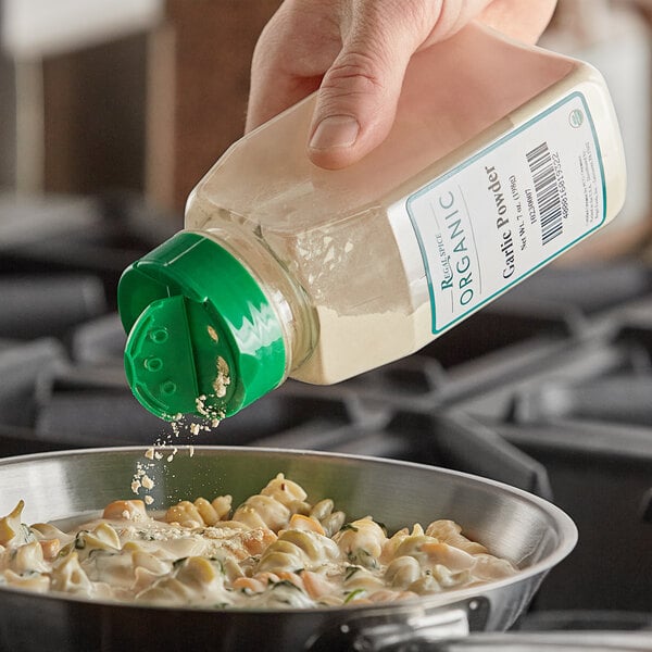 A person pouring Regal Organic Garlic Powder into a bowl of food.