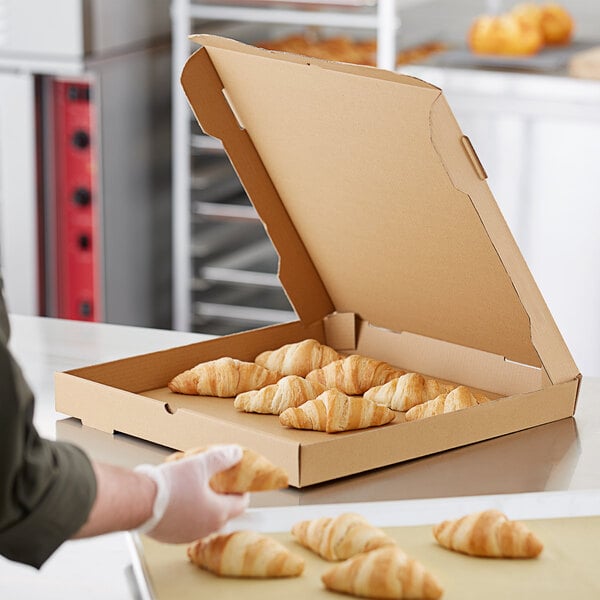 A person putting a croissant in a Choice Kraft pizza box.