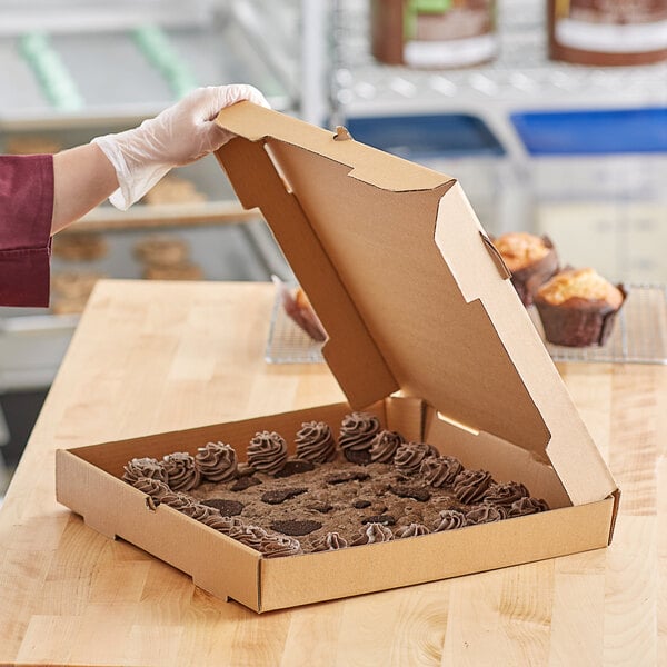 A person in gloves holding a Kraft Corrugated pizza box.