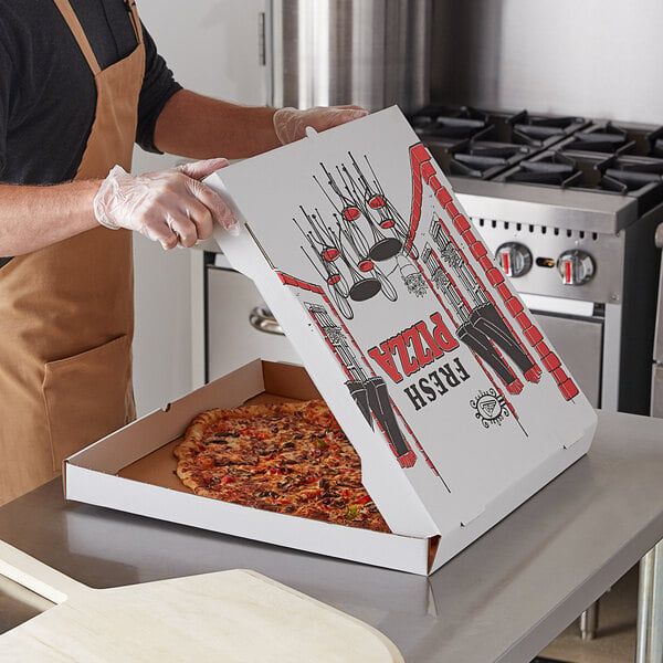 A man holding a Choice white corrugated pizza box with a pizza inside.