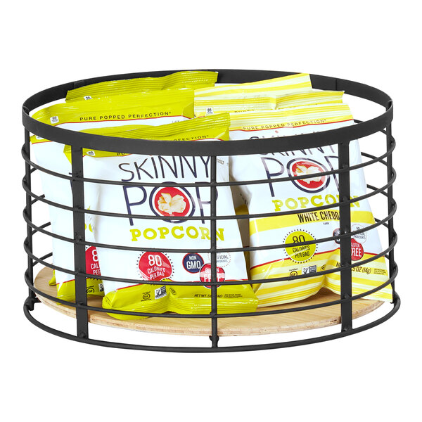 A black metal and bamboo display riser holding bags of popcorn on a bakery counter.